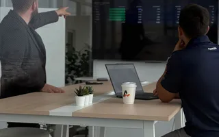 Two Azendo specialists reviewing dashboards on a wall screen in the Bangkok office