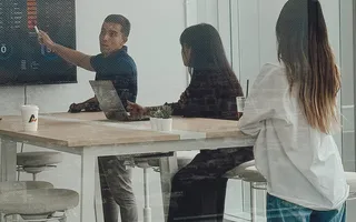 A colleague presenting on a wall screen to a small team in Bangkok