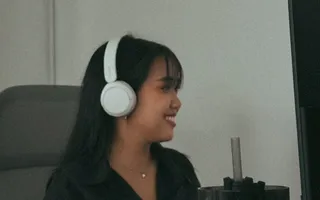 An Azendo specialist wearing headphones and smiling at her desk in Bangkok