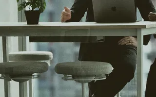 A colleague working on a laptop at a high table by the Bangkok office windows