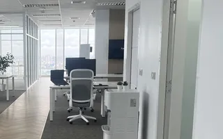 Desks and a corridor at the Bangkok office, with the city skyline through the windows