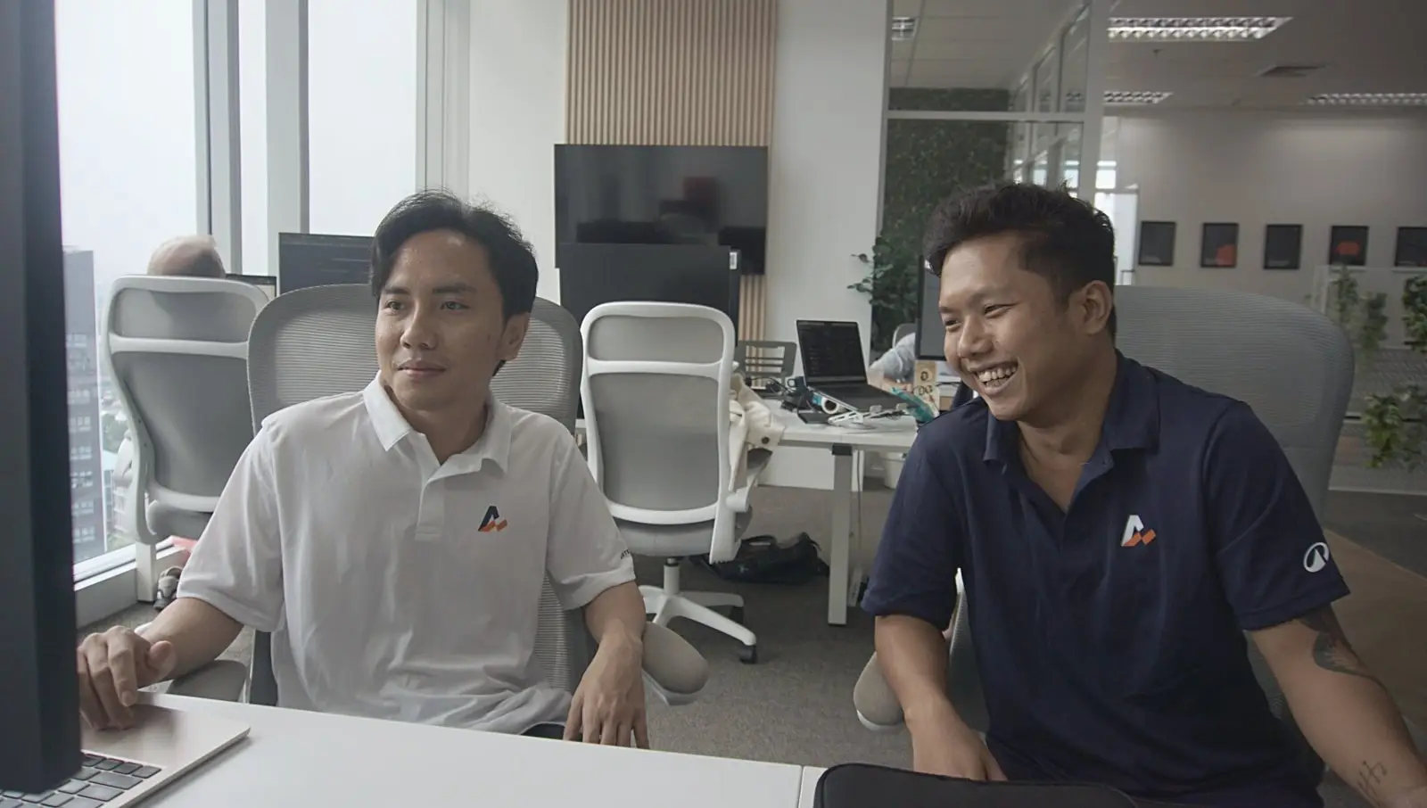 Two members of our offshore development team sharing a laugh at their desks