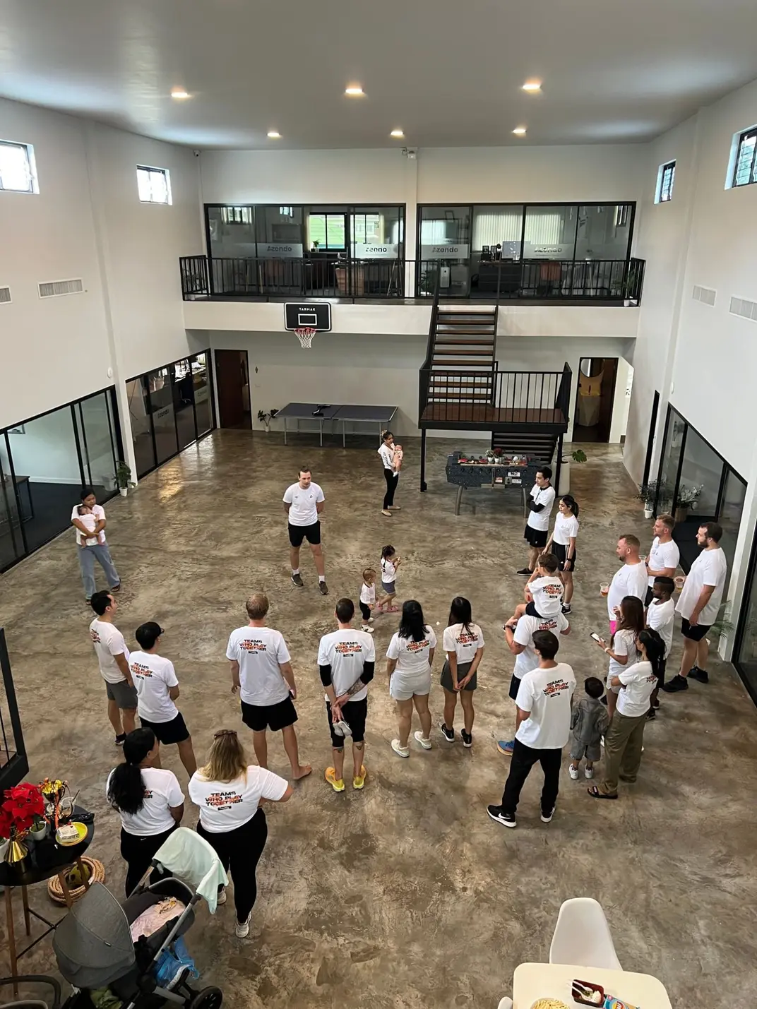 Our dedicated offshore team in a circle in the hall, wearing Teams who play together shirts