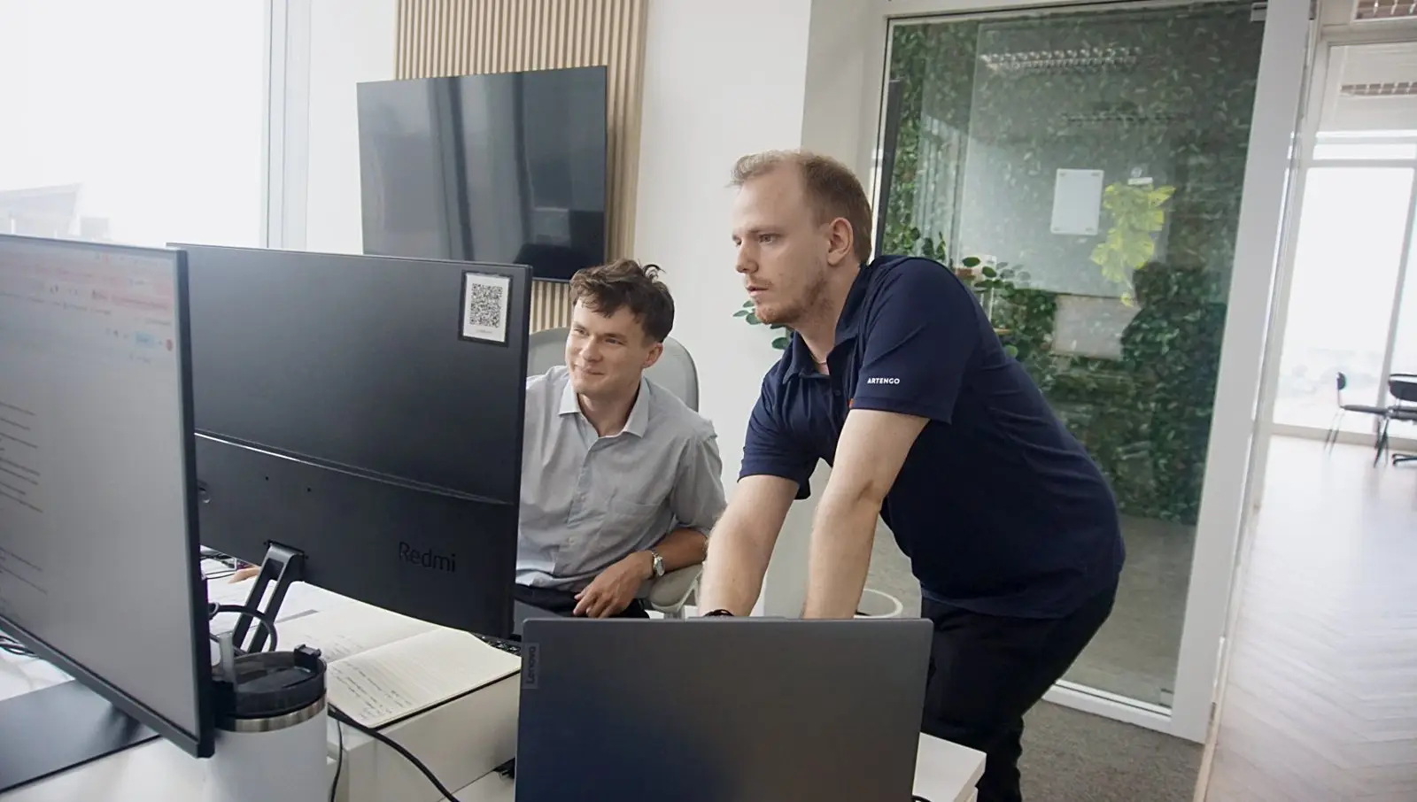 Two offshore developers reviewing work together at a monitor in Bangkok