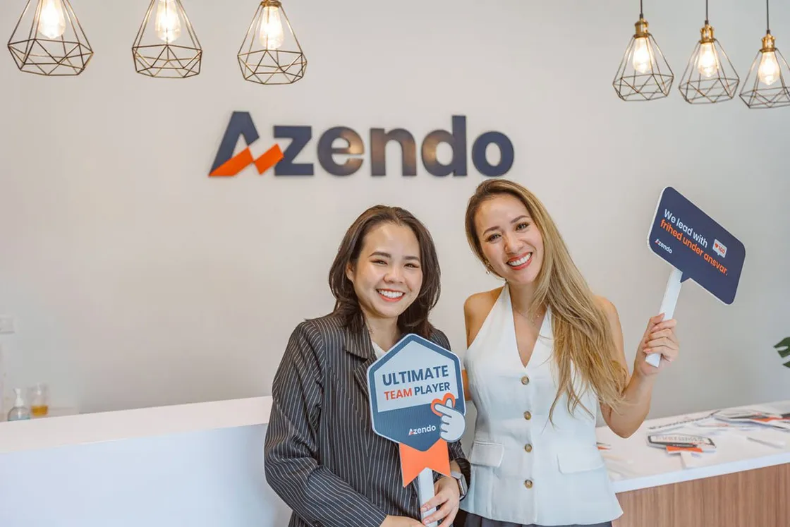 Two Azendo team members holding the Ultimate team player and frihed under ansvar signs