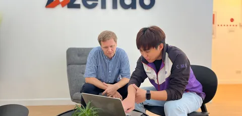 Two Azendo colleagues working through a problem on a laptop in Chiang Mai