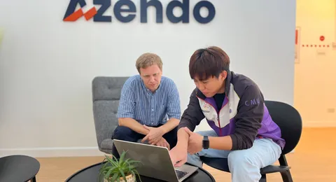 Two developers at Azendo, an offshore software development company, working on a laptop in Chiang Mai