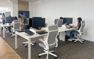 The team at their desks in the Bangkok office, with the skyline through the windows