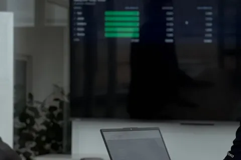 Two Azendo specialists reviewing dashboards on a wall screen in the Bangkok office