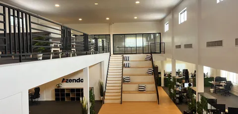 The open-plan Azendo office in Chiang Mai, with a central staircase and mezzanine