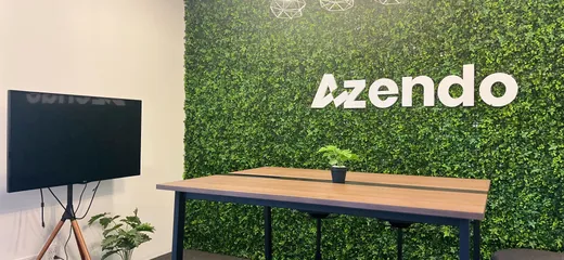 A standing meeting table in front of the green Azendo logo wall in Chiang Mai