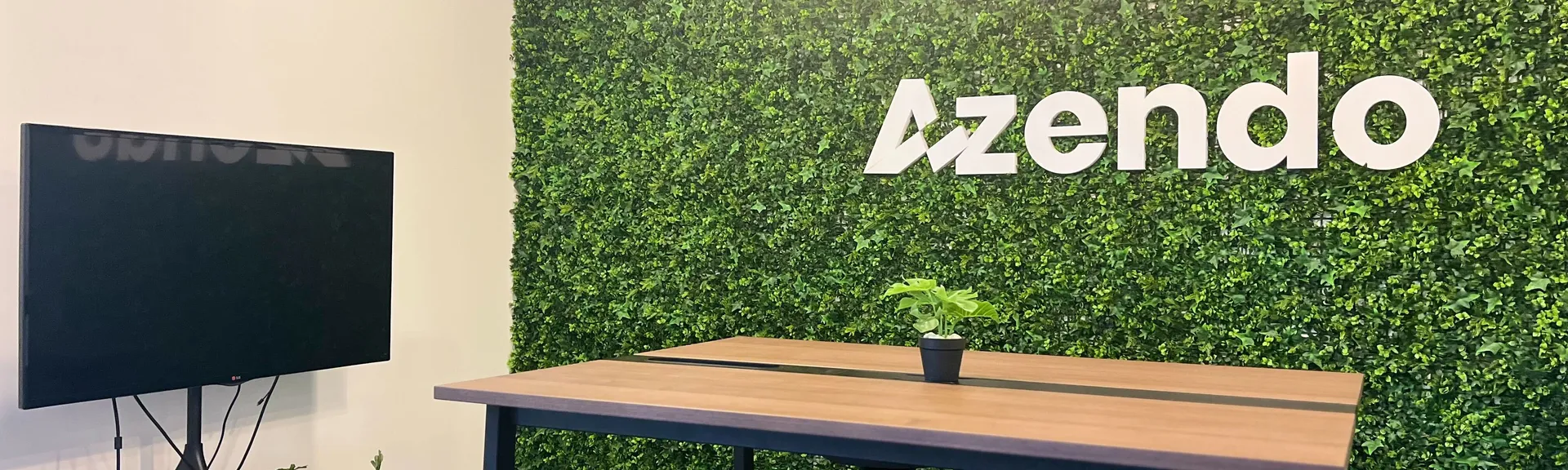 A standing meeting table in front of the green Azendo logo wall in Chiang Mai