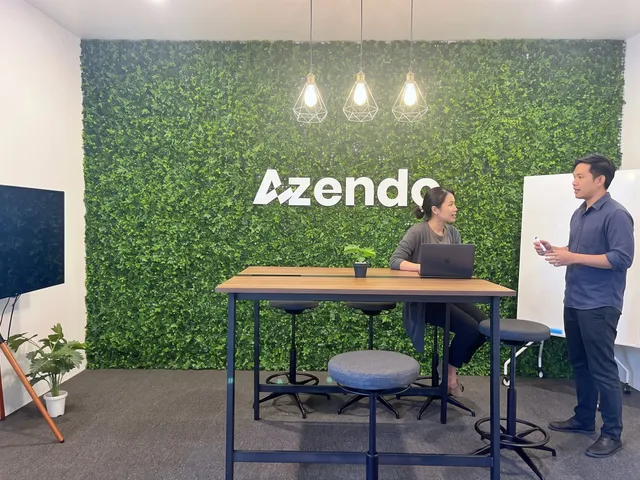Two offshore developers in Thailand talking by the green wall during the shared working day