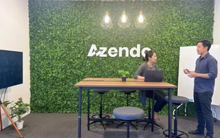 Two team members at the standing table by the green wall in Chiang Mai