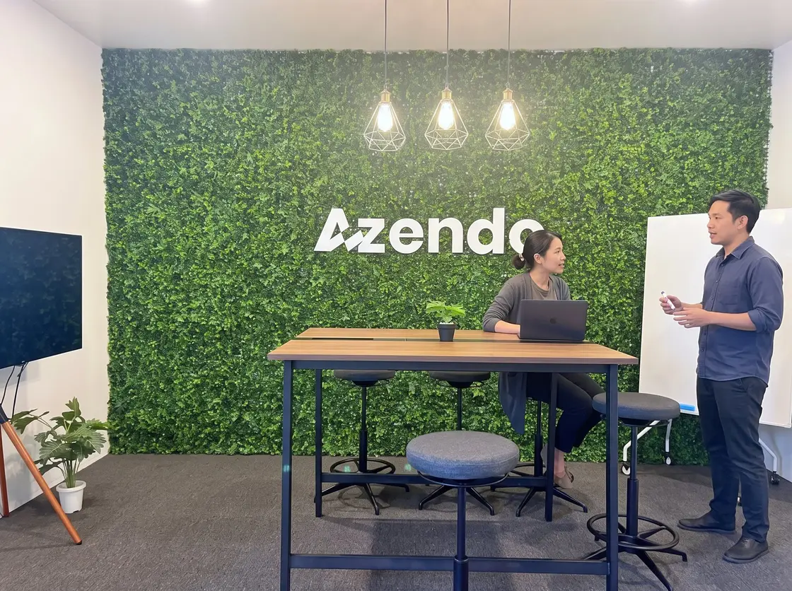 Two members of our offshore software development team talking by the green wall in Chiang Mai