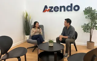 Two members of a dedicated team talking in the reception corner under the Azendo logo