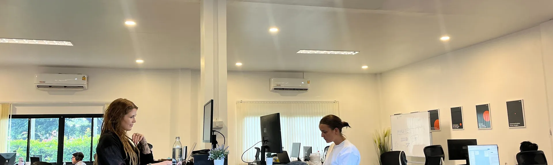 Two specialists working at standing desks in the open-plan Chiang Mai office