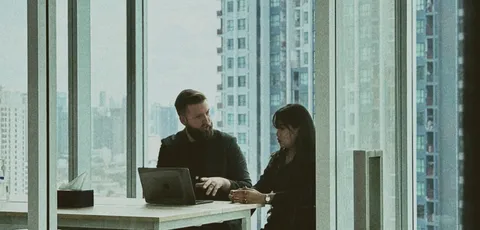 Two colleagues in a one-to-one meeting at a window table in the Bangkok office