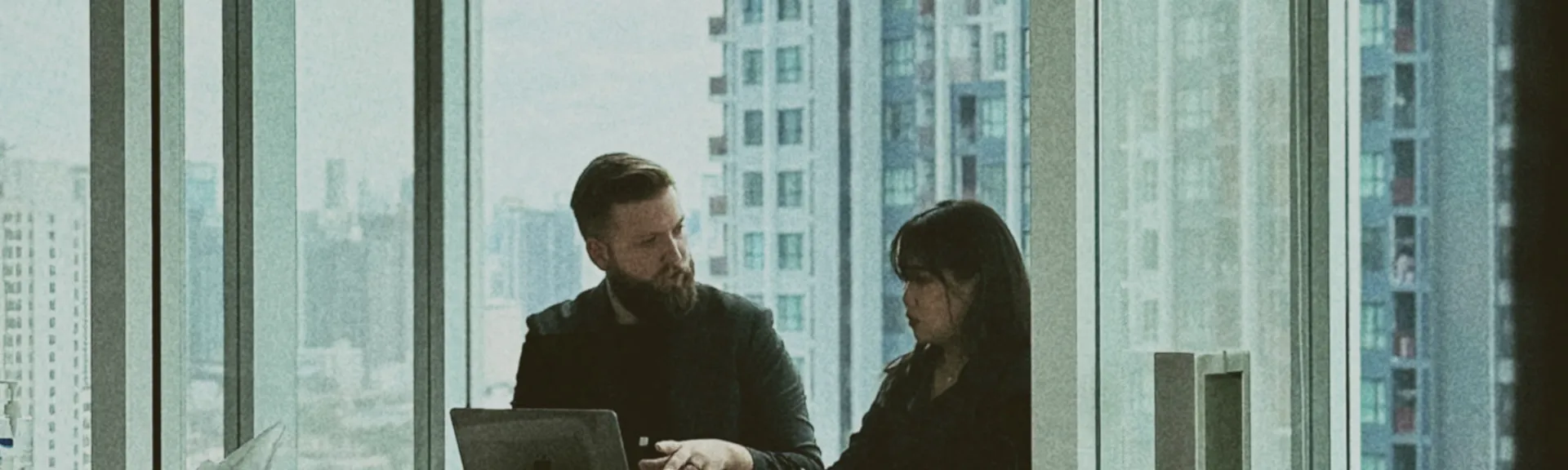 Two colleagues reviewing analysis by a Bangkok office window, part of our data science services