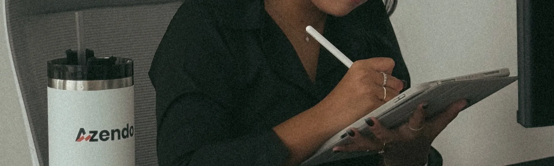 A designer wearing headphones sketching on a tablet at her desk
