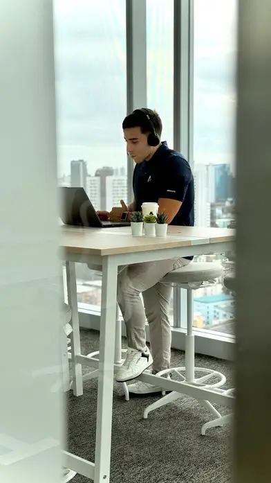 One of our offshore software developers coding with headphones by the Bangkok office windows