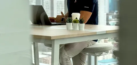 A specialist wearing headphones working on a laptop by the Bangkok office windows