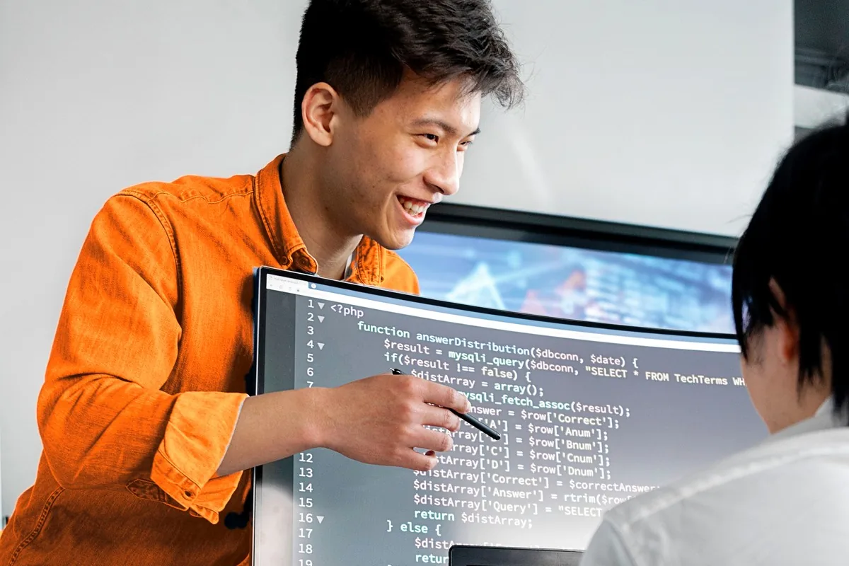 Two offshore developers on a dedicated team walking through code on a large screen