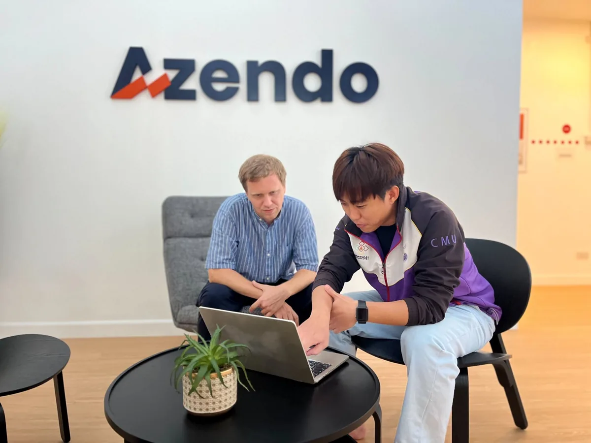 An experienced engineer and a developer from an offshore team working through a task together at a laptop